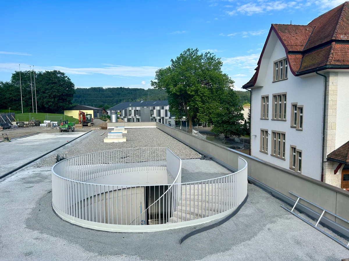 Man sieht die neue Sporthalle zwischen den bestehenden Schulhäusern.